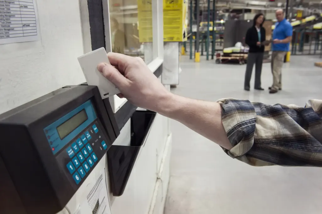 Person clocking in at a factory time clock card utc