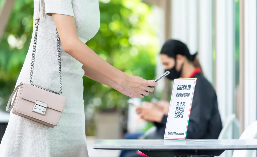 woman using phone to scan a qr code and check in
